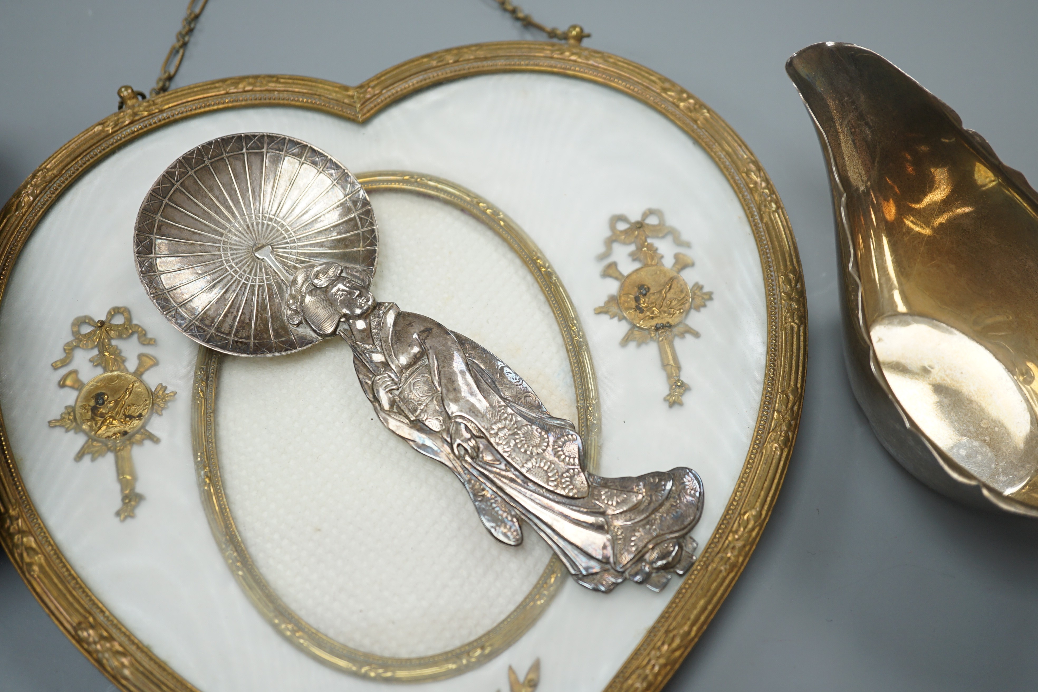 A 19th century gilt heart-shaped frame, A Japanese sterling figural spoon, a 1930's silver cream jug and modern silver mounted clock, photo frame 20 cms high.